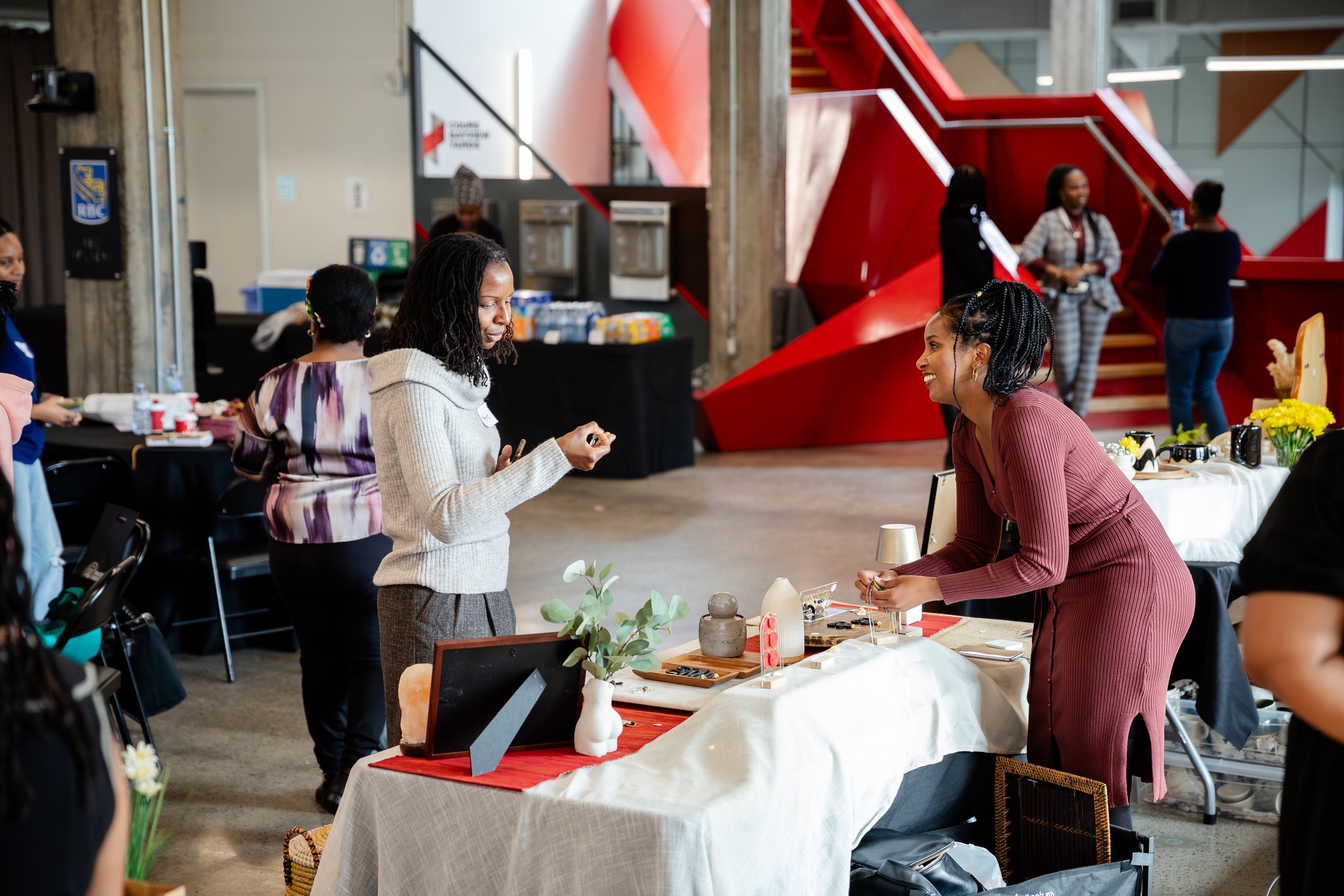 Students work together at tables in a modern collaborative workspace with red architectural details.