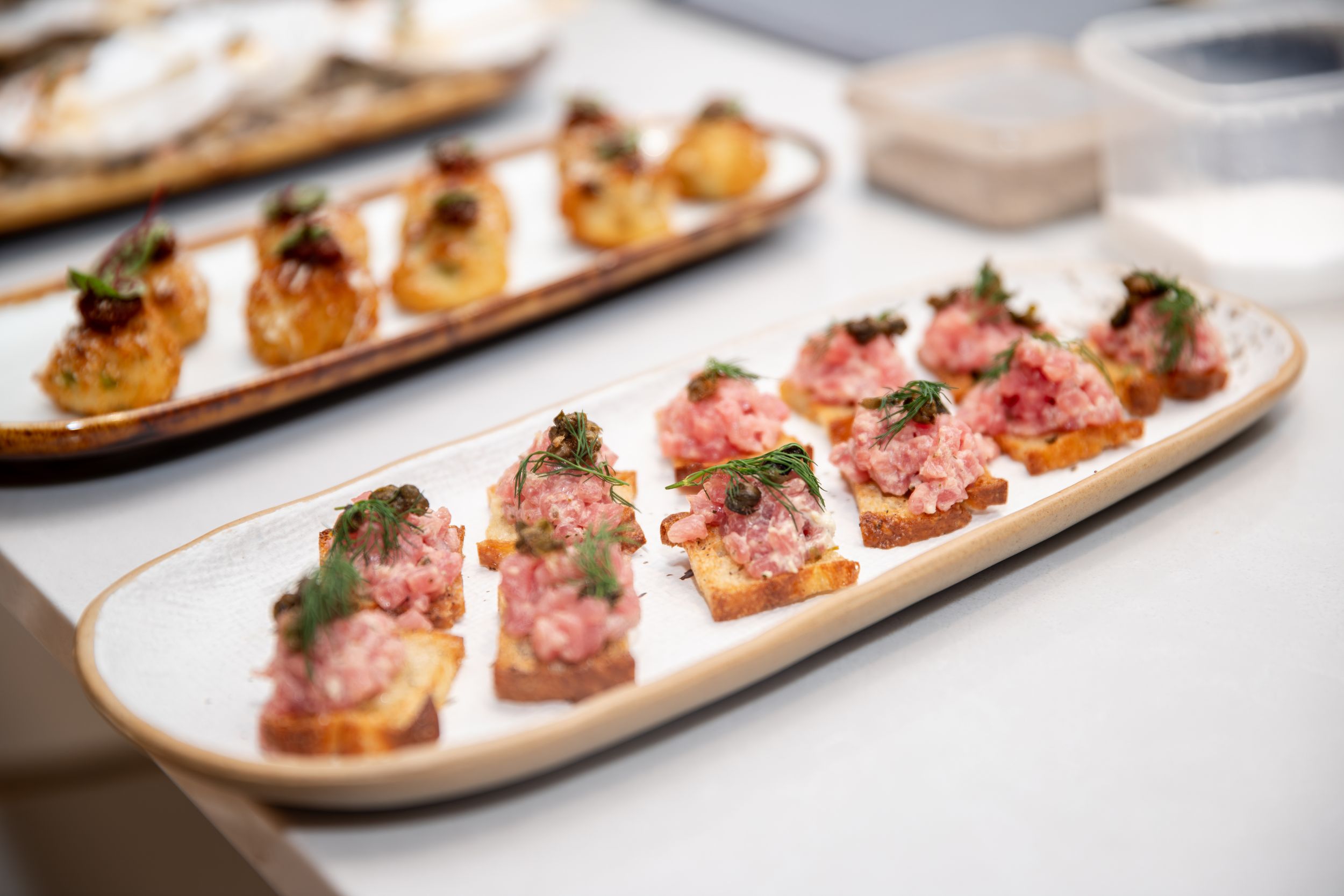 Wooden serving boards with assorted appetizers arranged in a row on a white surface.