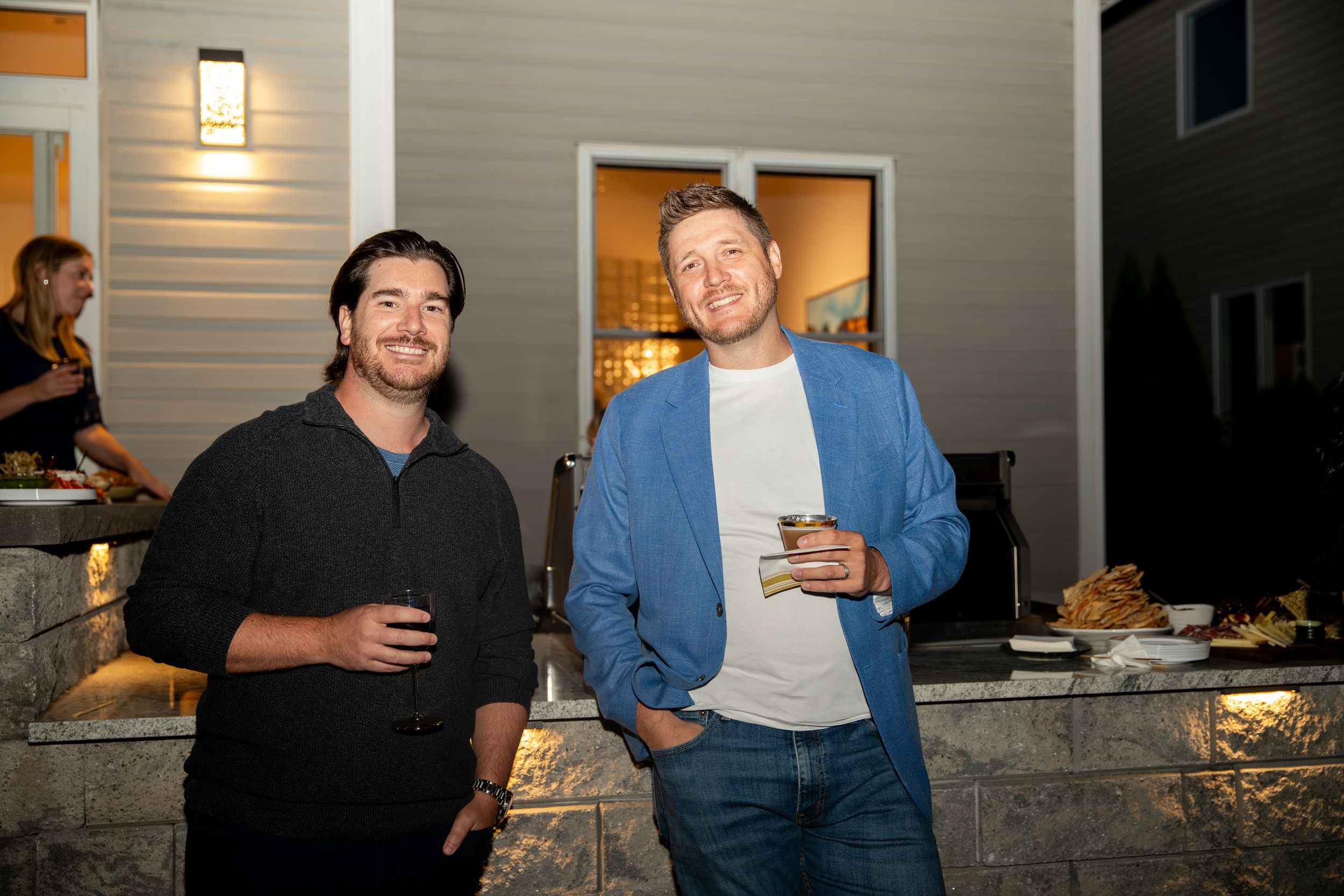 People enjoying drinks and conversation at a casual evening gathering in a modern kitchen setting.