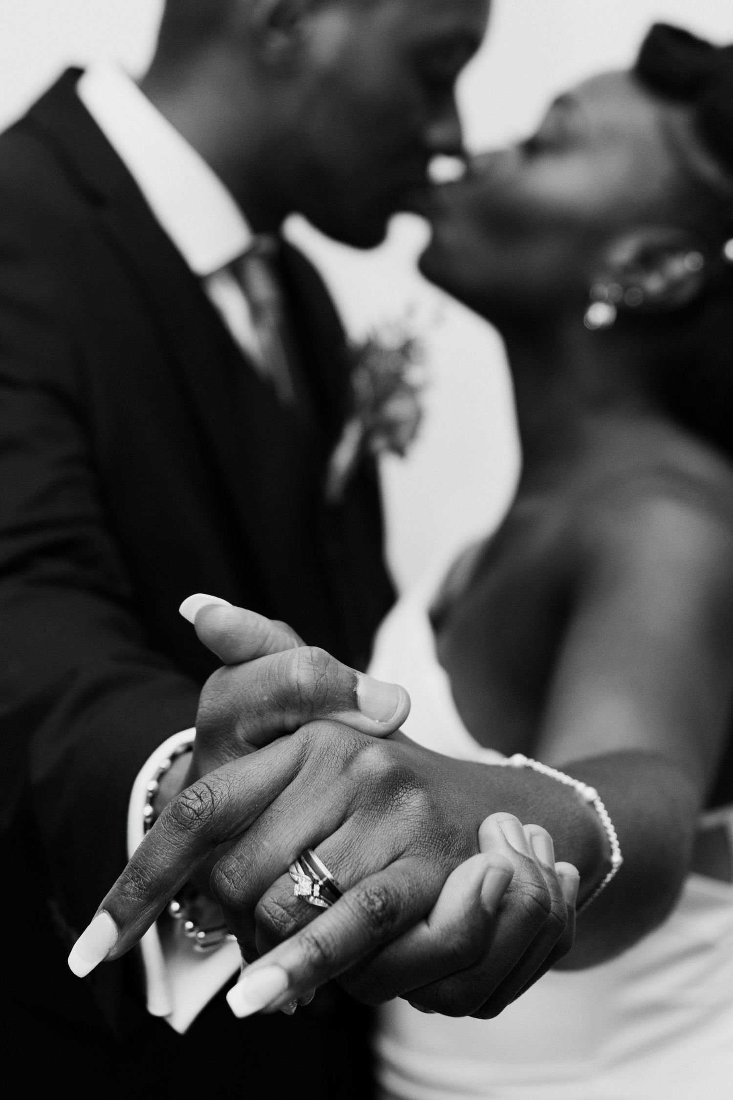 Close-up black and white photo of newlywed couple's hands with wedding rings.
