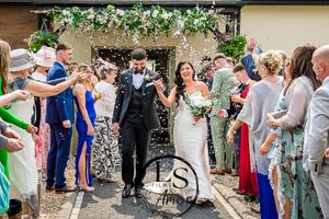 Wedding guests shower confetti on the newlyweds as they exit the ceremony.