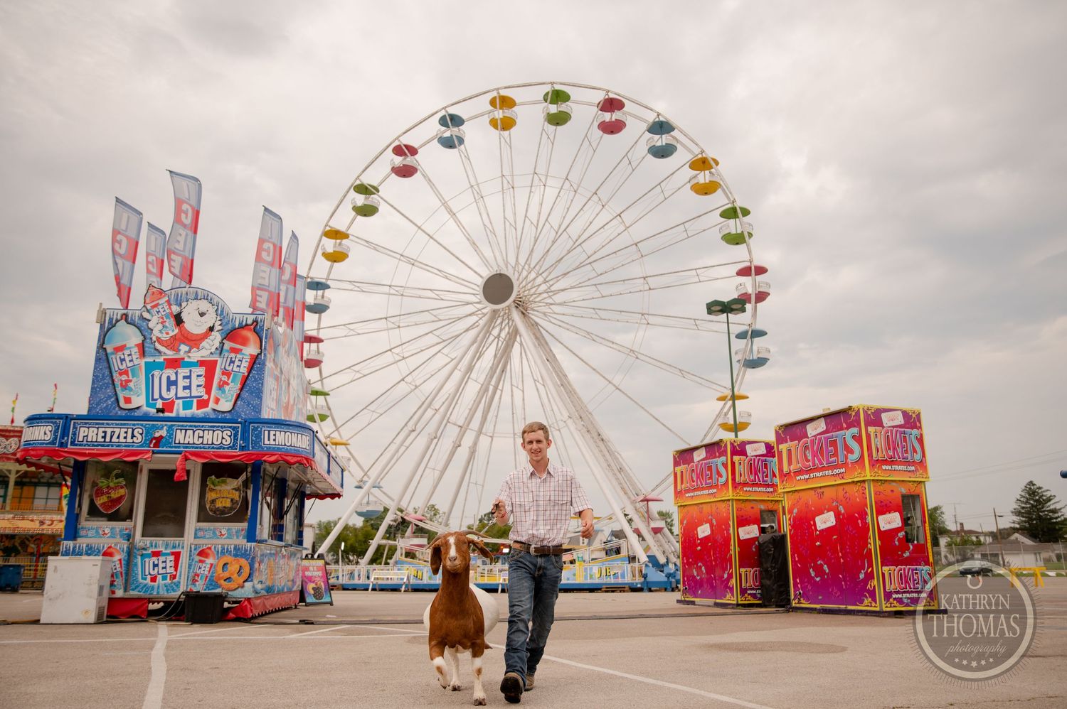 A classic carnival scene with rides and a Ferris wheel against a cloudy sky at a county fair.