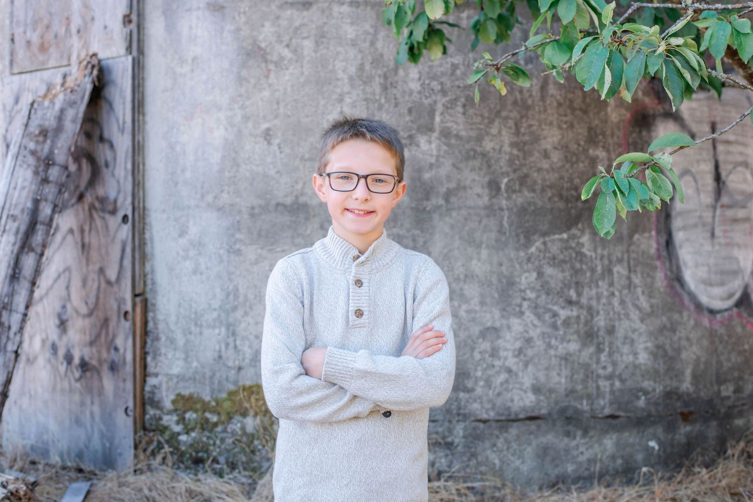 Portrait series of young person in glasses and sweater against concrete background.