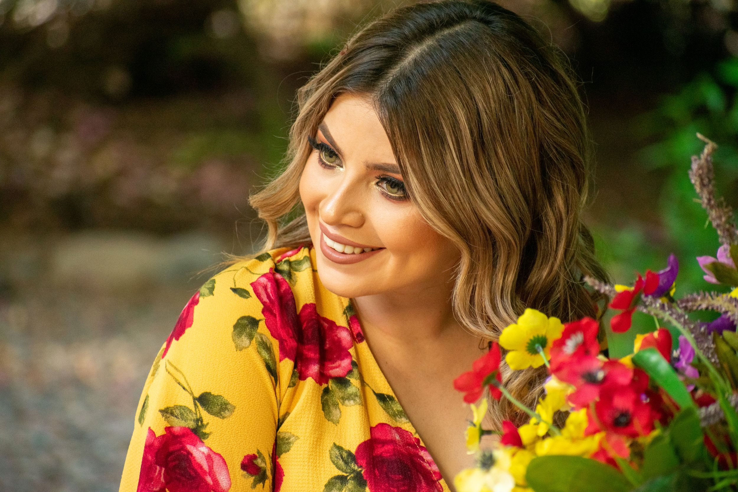 Portrait surrounded by vibrant red and yellow flowers in natural outdoor setting.