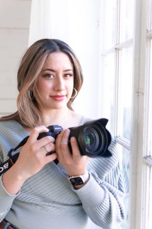Photographer with camera by window in natural lighting.