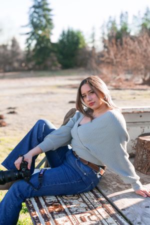 Photographer relaxing on vintage truck bed while holding camera equipment.