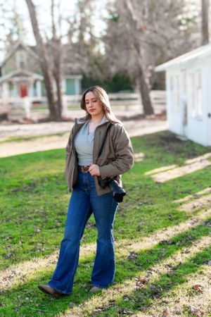 Casual outdoor portrait with camera gear and comfortable jacket in spring setting.