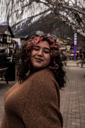 Candid street portrait with brown sweater against urban backdrop.