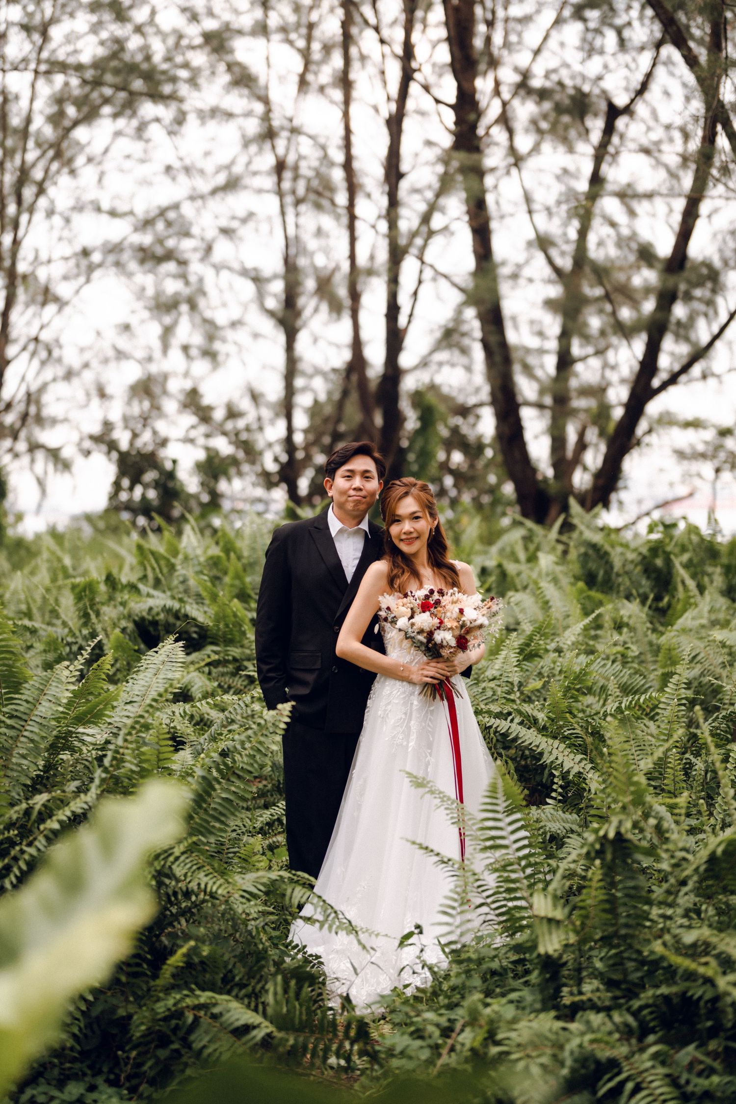 Wedding couple poses in enchanted forest setting with natural greenery.