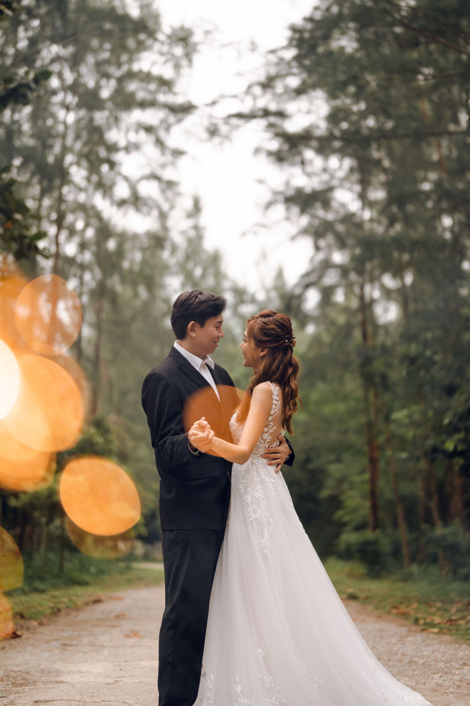Wedding couple embracing in forest with sparklers creating magical lighting effects.
