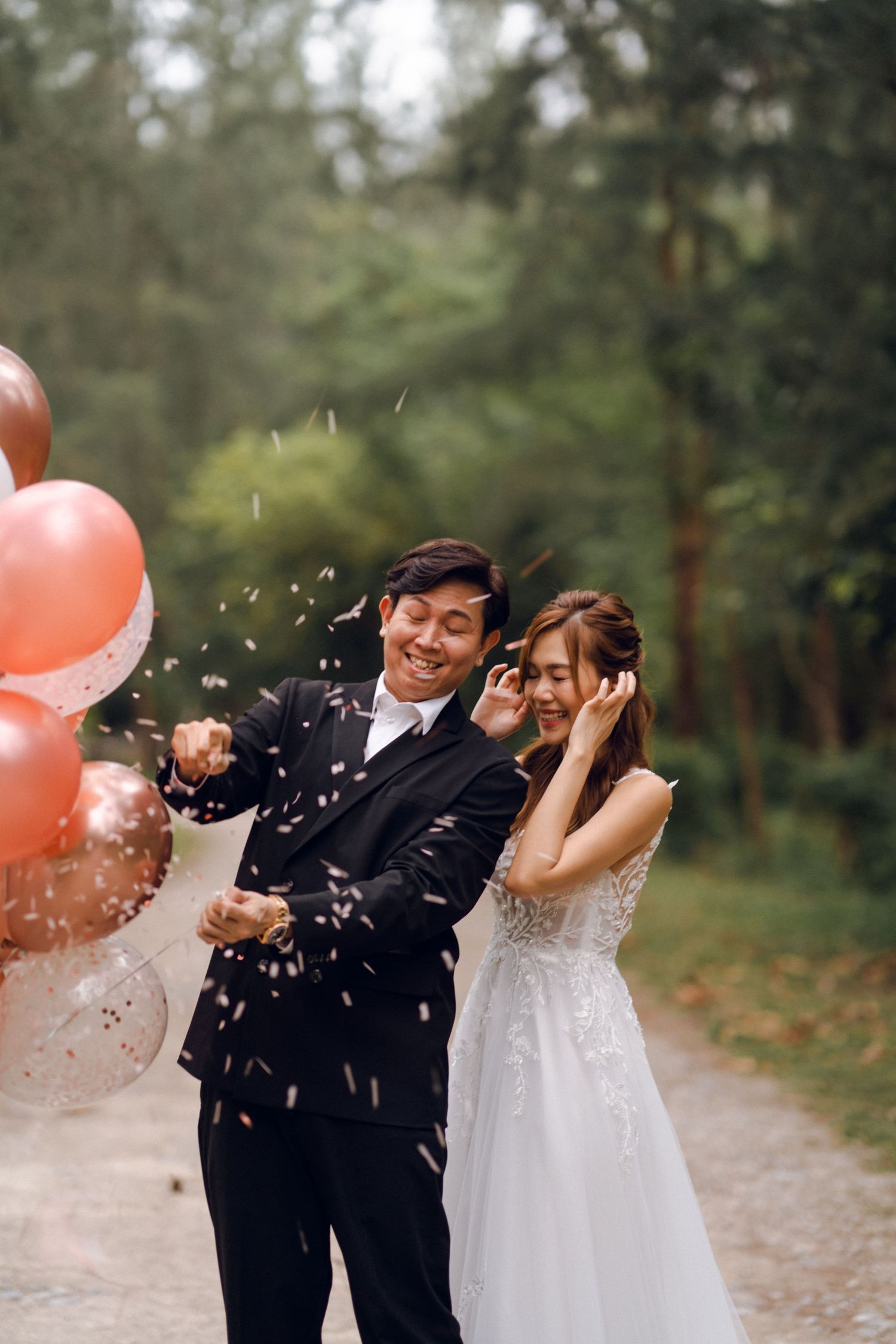 A joyful wedding couple reacts to confetti being thrown during their forest photoshoot.