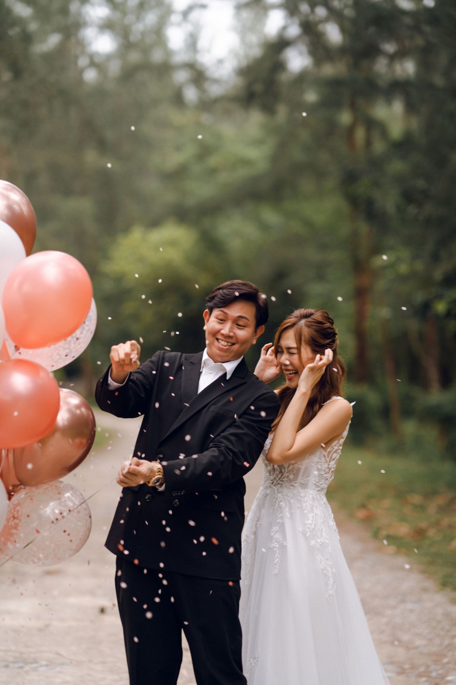 A couple laughs together as confetti falls around them during their wedding photoshoot.