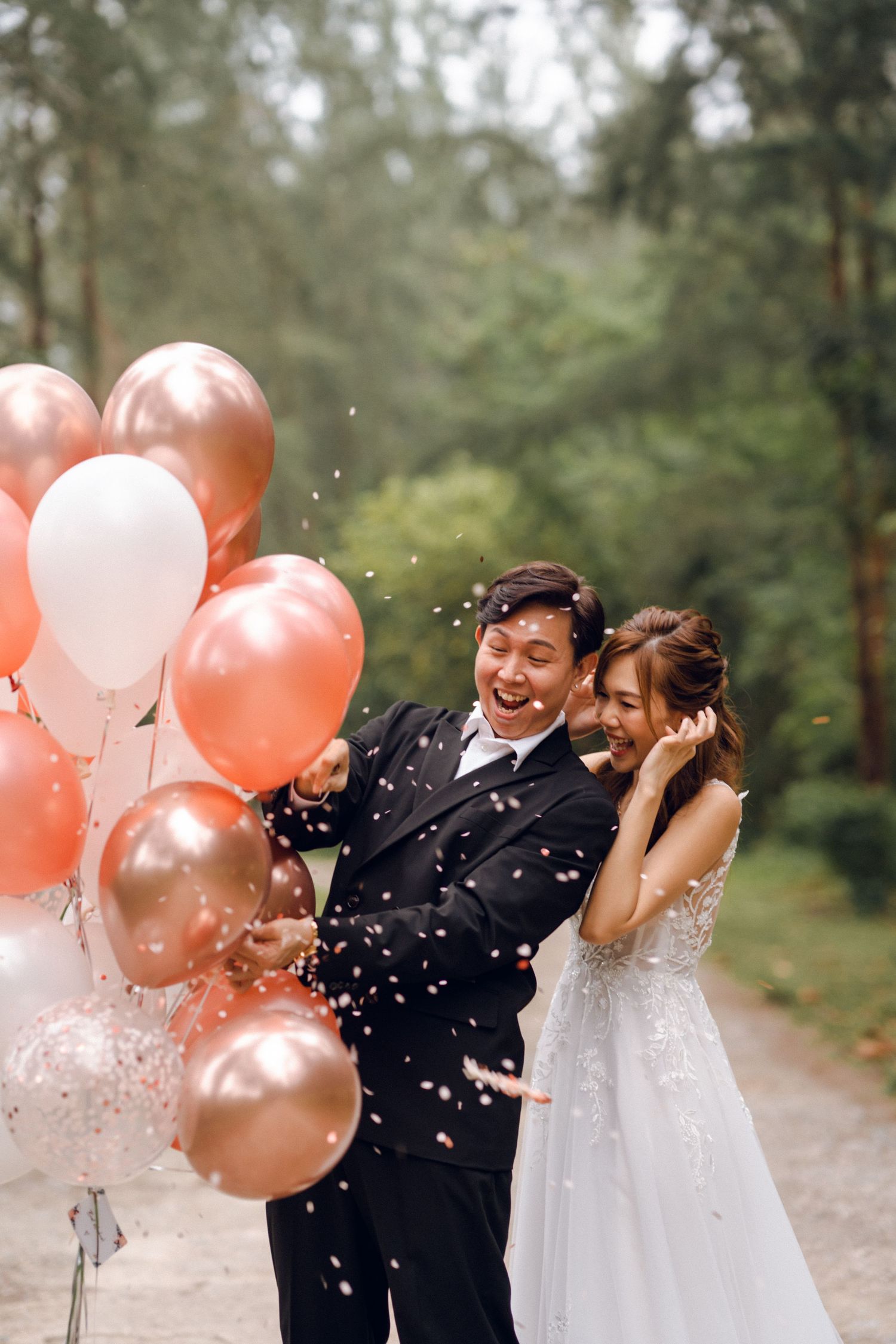 A celebratory moment with peach balloons and confetti during a forest wedding shoot.