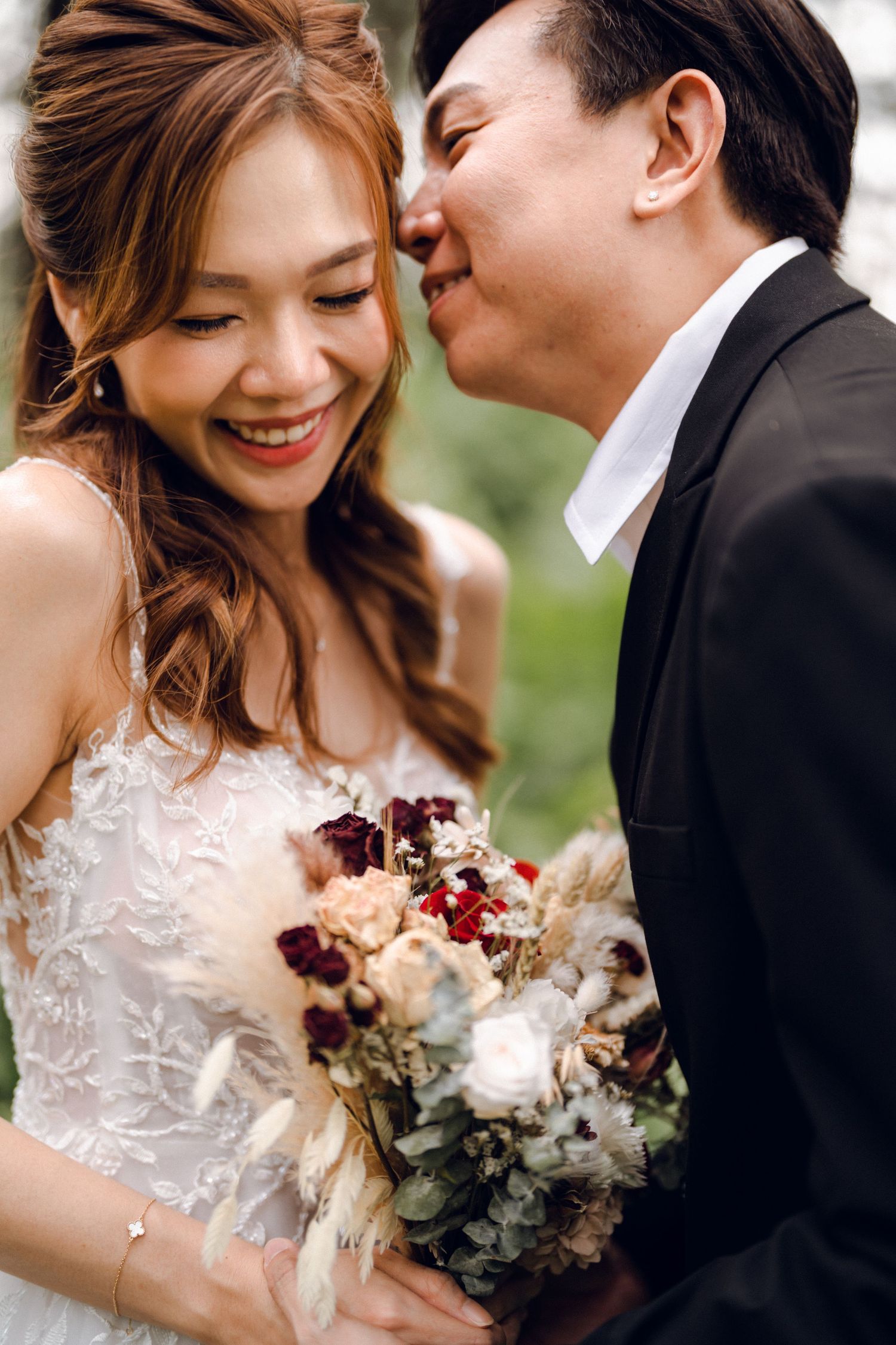 Intimate wedding portrait with bride holding elegant bouquet of burgundy and white flowers.