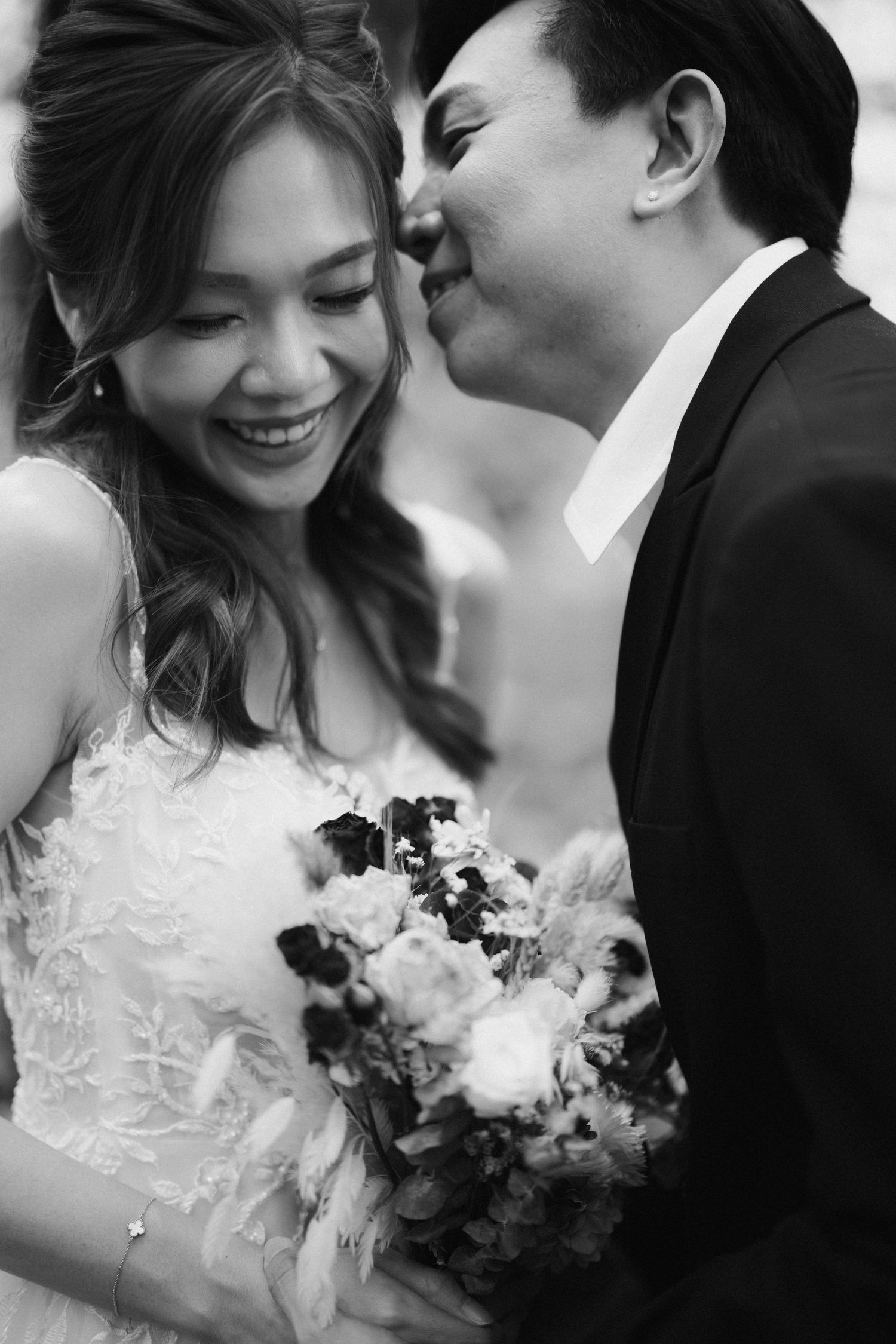Black and white wedding photo capturing tender moment between newlyweds.