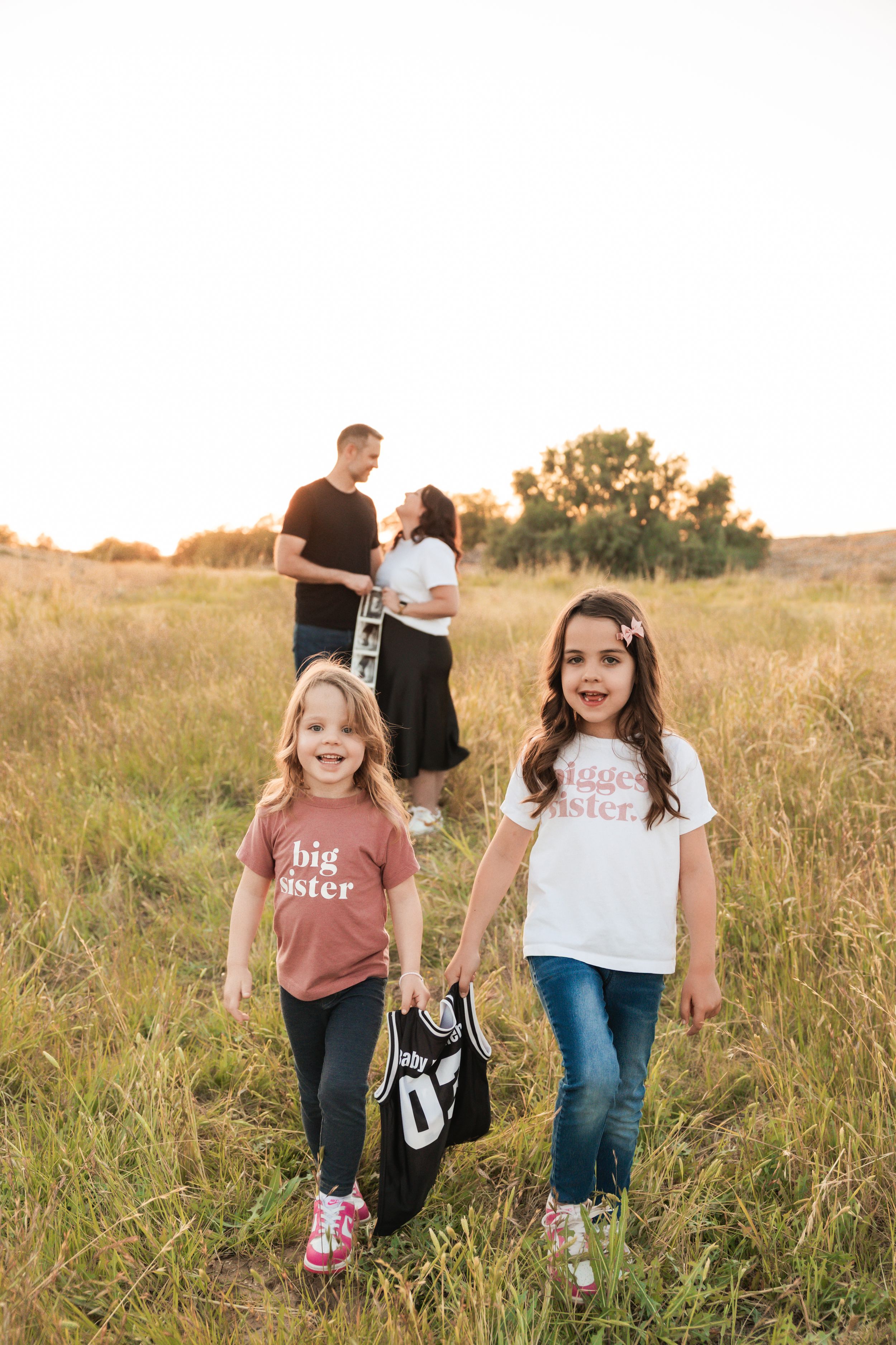 Friends in casual outfits share fun moments together in a golden sunlit meadow with tall grass and florals.