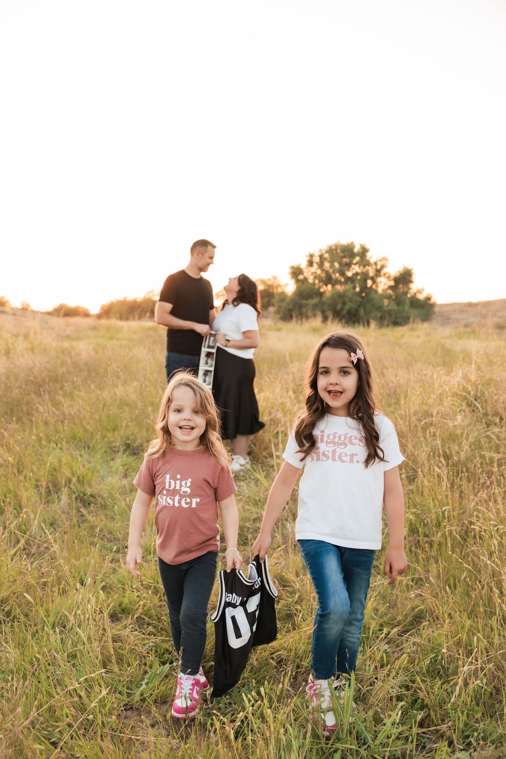 Friends in casual outfits share fun moments together in a golden sunlit meadow with tall grass and florals.