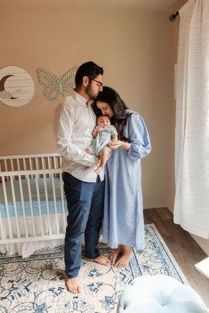 A series of candid family moments on a blue and white patterned rug in a minimalist nursery setting.