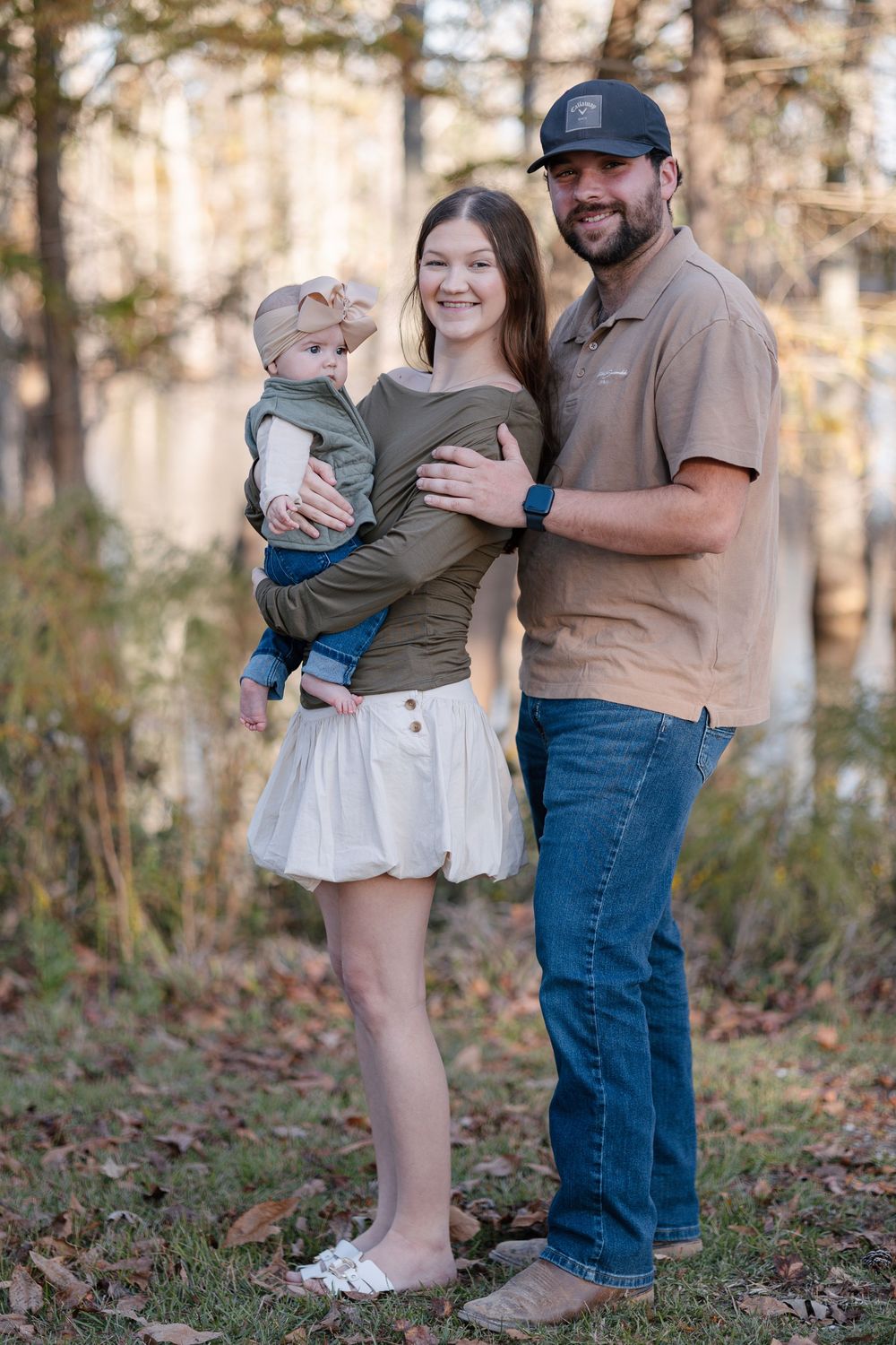 A family embraces while standing in a wooded area during a golden hour photo session.