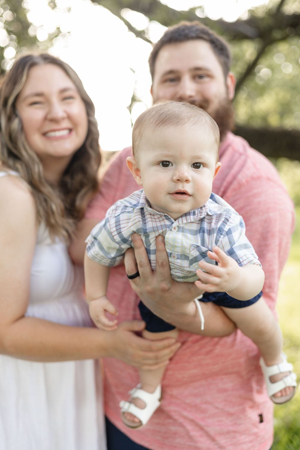 A happy family moment captured outdoors with a baby in blue plaid clothing.