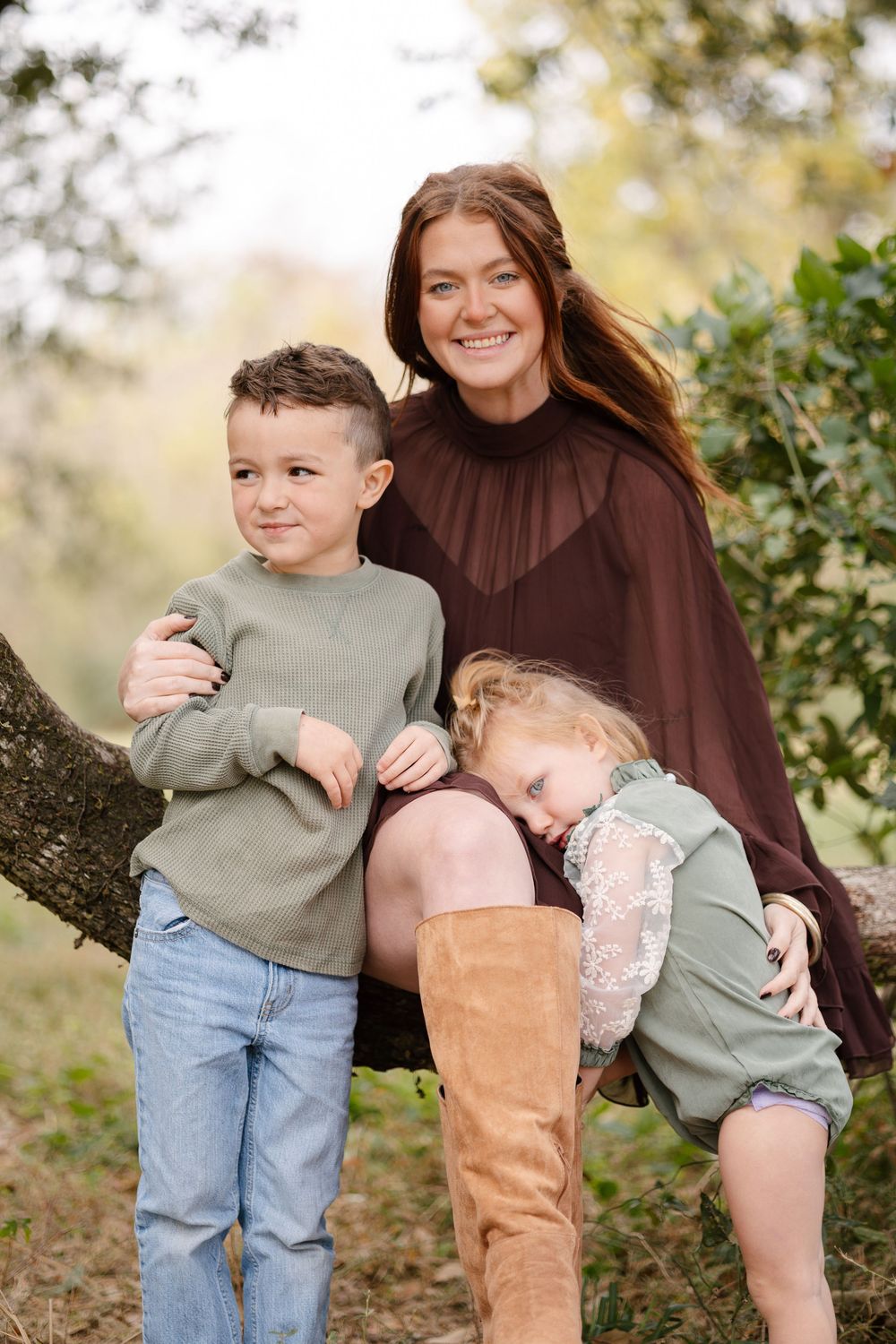 A family shares a playful moment together outdoors in casual clothing against a natural autumn background.