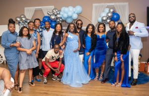 Group photo at celebration event with blue and silver balloon decorations.