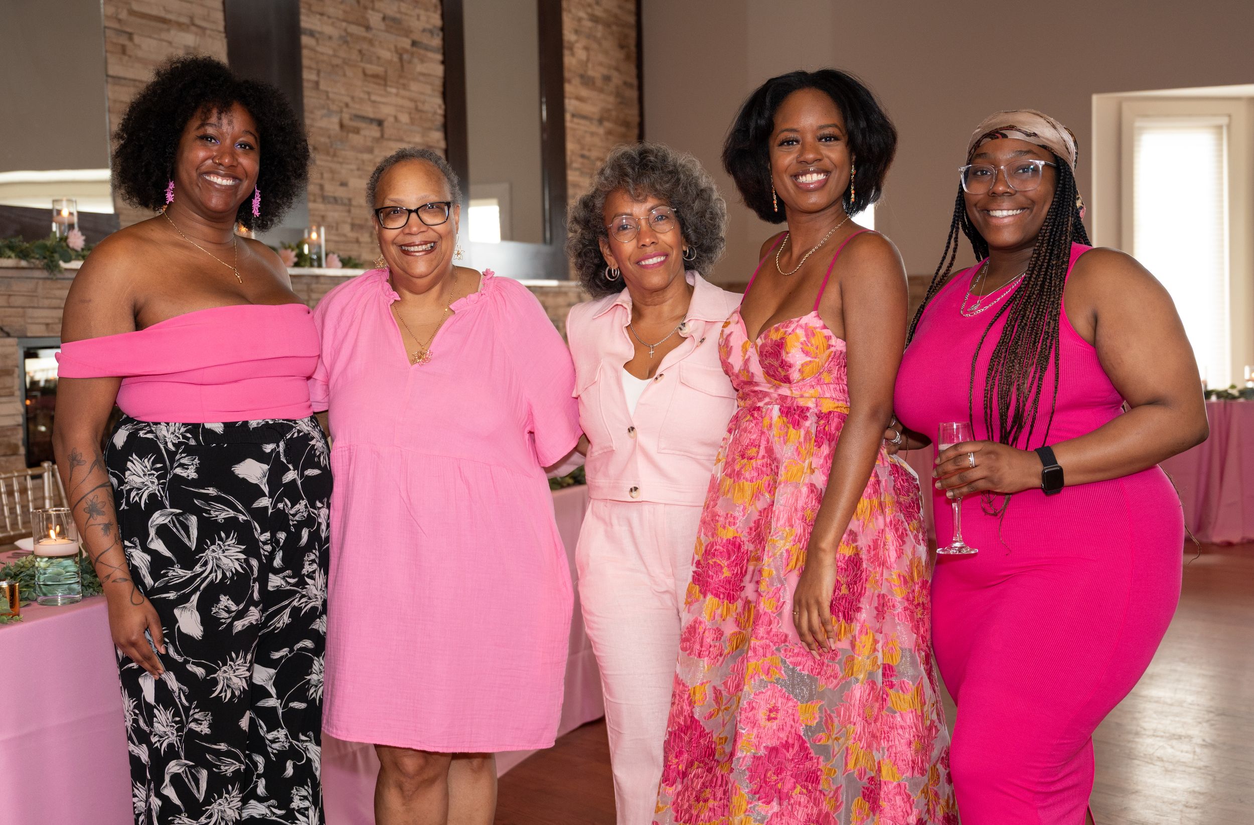 Group photo showing attendees wearing pink and floral dresses at a formal celebration.