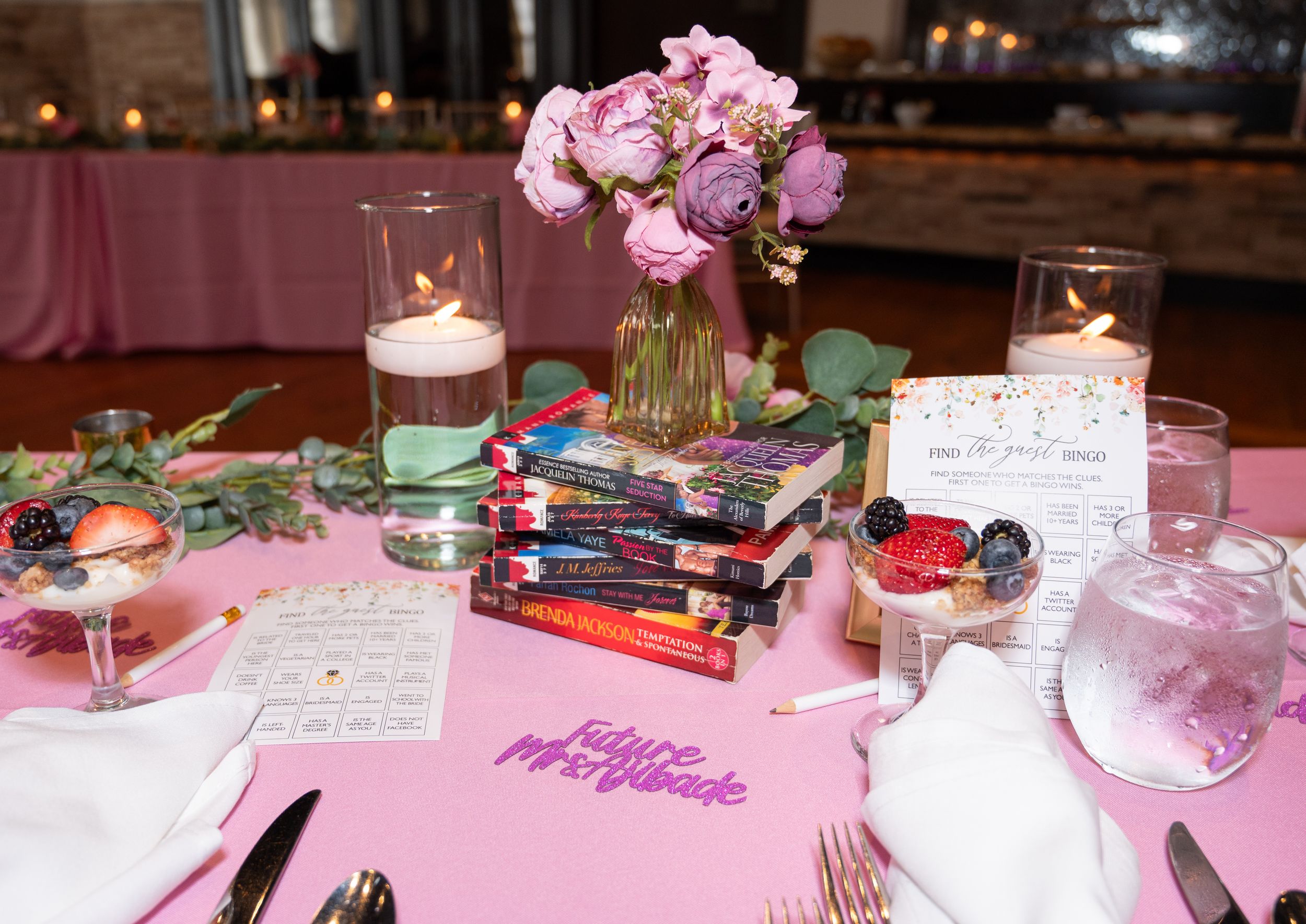 Pink table settings and floral centerpieces create an elegant reception layout with candlelit ambiance.