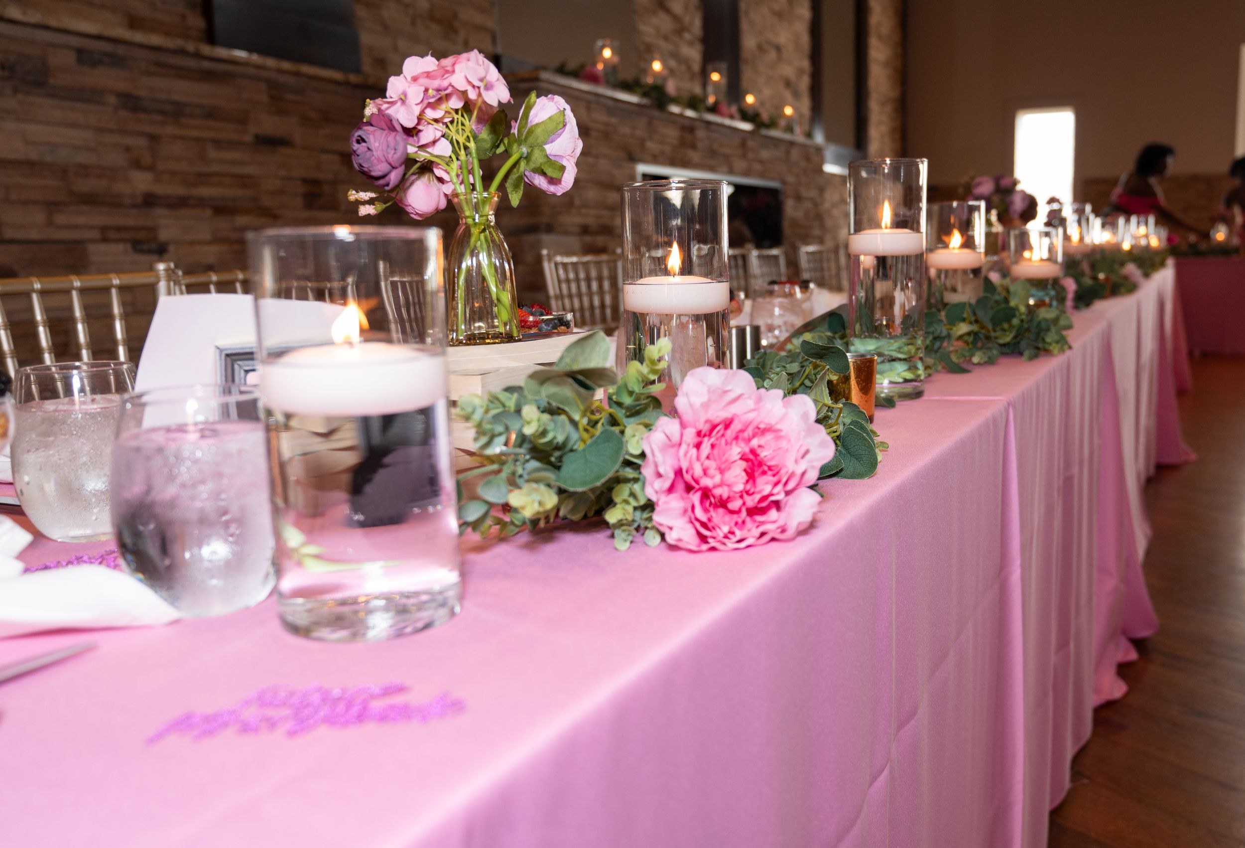 Long banquet tables decorated with pink linens and orchid centerpieces in an event space.