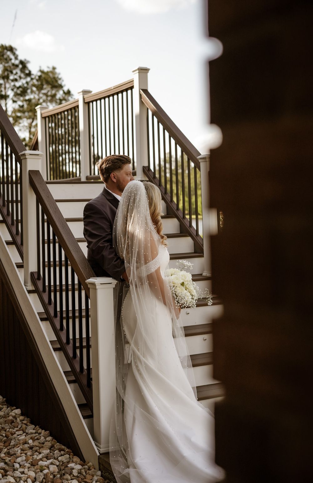 Bride and groom share a quiet moment on the stairs of a beautiful wedding venue in Middle Georgia, captured with timeless cinematic beauty.