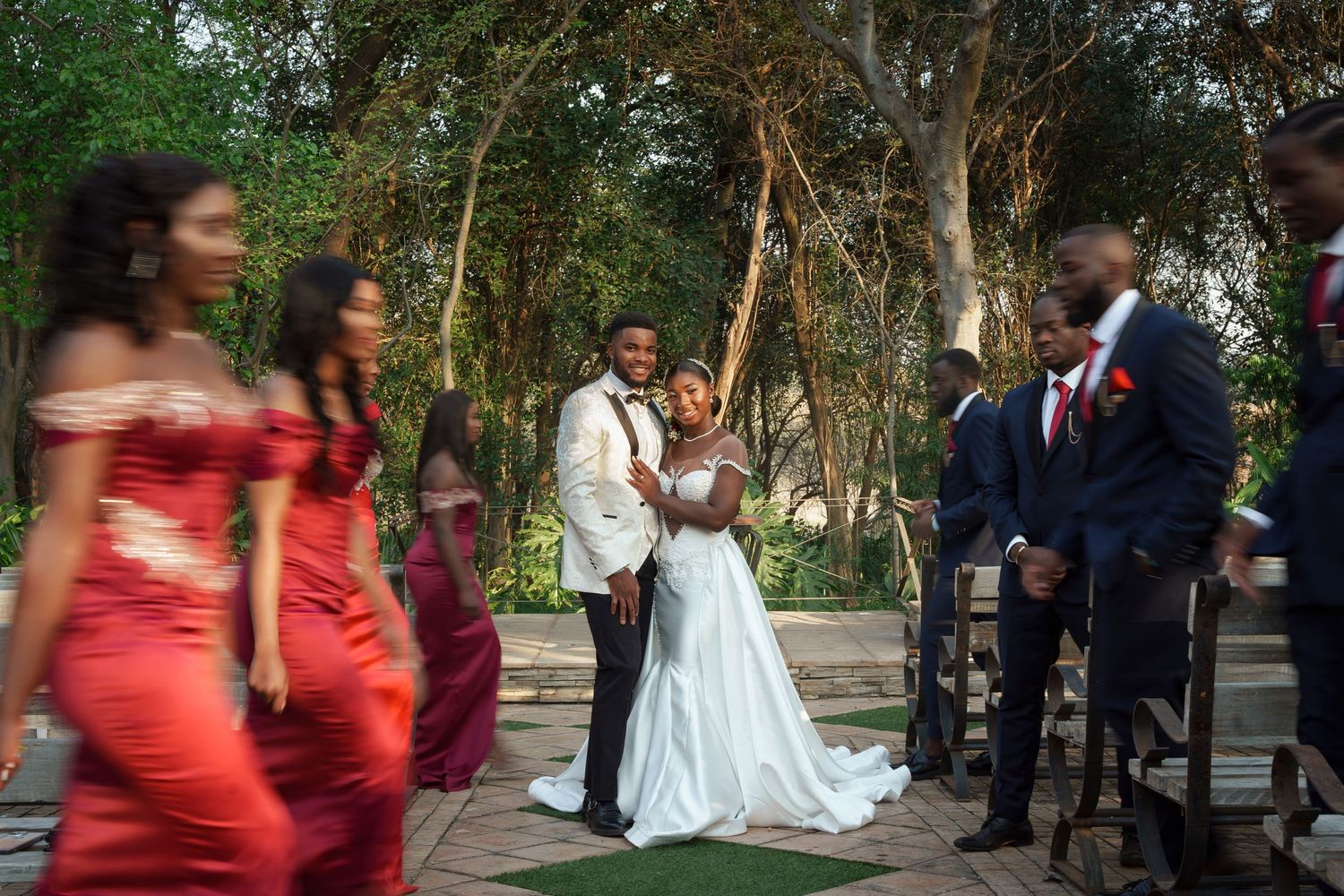 Wedding ceremony in progress at outdoor venue with bridesmaids in coral dresses.