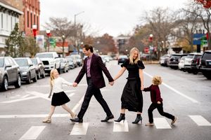 A family walks across a crosswalk in a city street, recreating the iconic Abbey Road album cover pose.