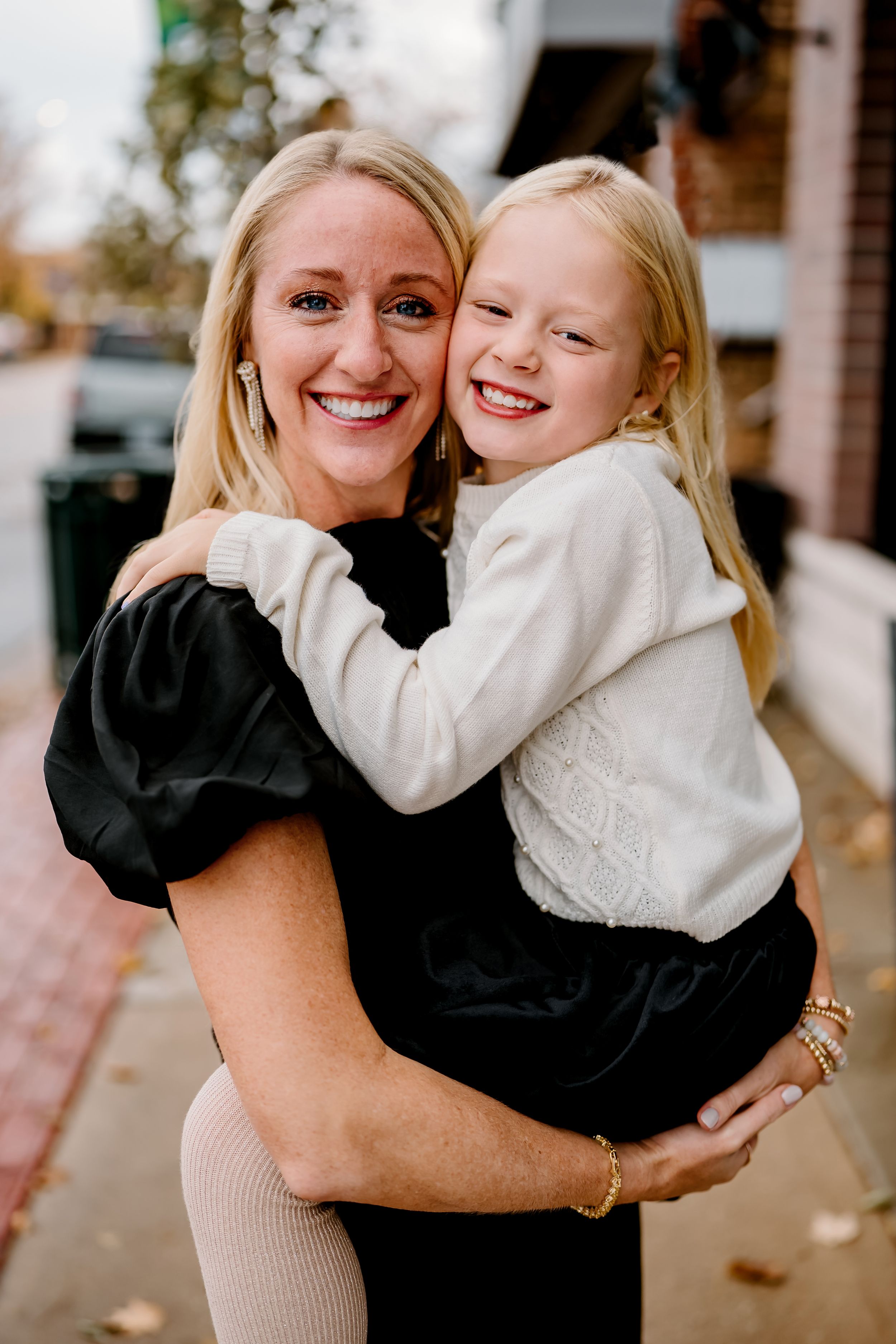 A series of candid photos showing joyful embraces between two people wearing black and white outfits outdoors.