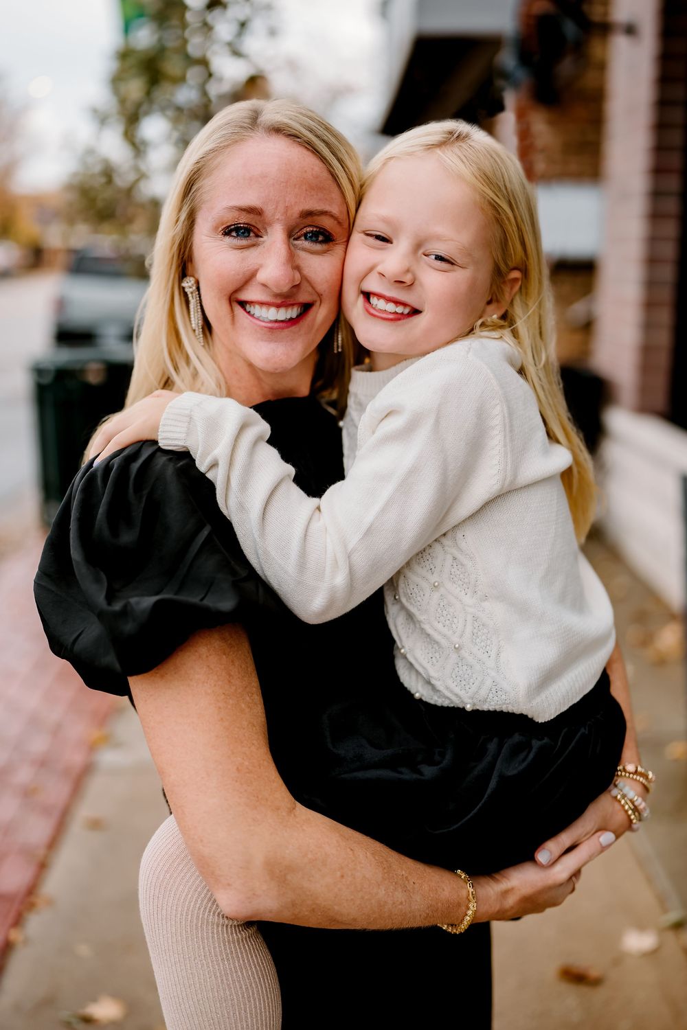 A series of candid photos showing joyful embraces between two people wearing black and white outfits outdoors.