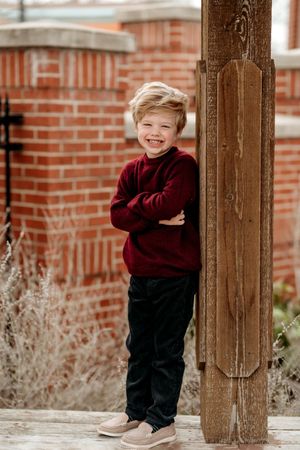 A playful sequence of photos showing someone in a burgundy sweater peeking around a wooden post against brick walls.