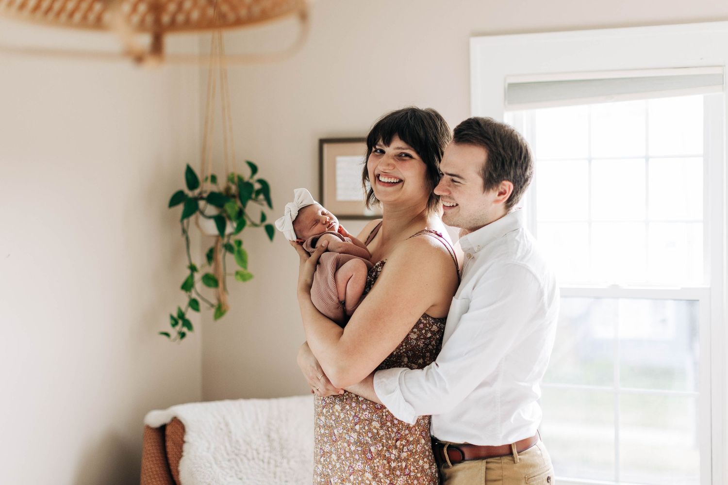 Intimate family portrait in a sun-filled room with minimalist decor.
