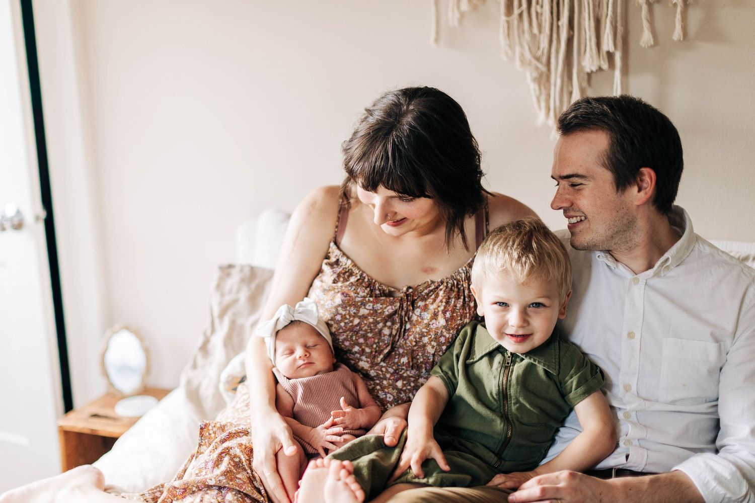 Happy family spending quality time together on a white bed during an intimate indoor photoshoot.