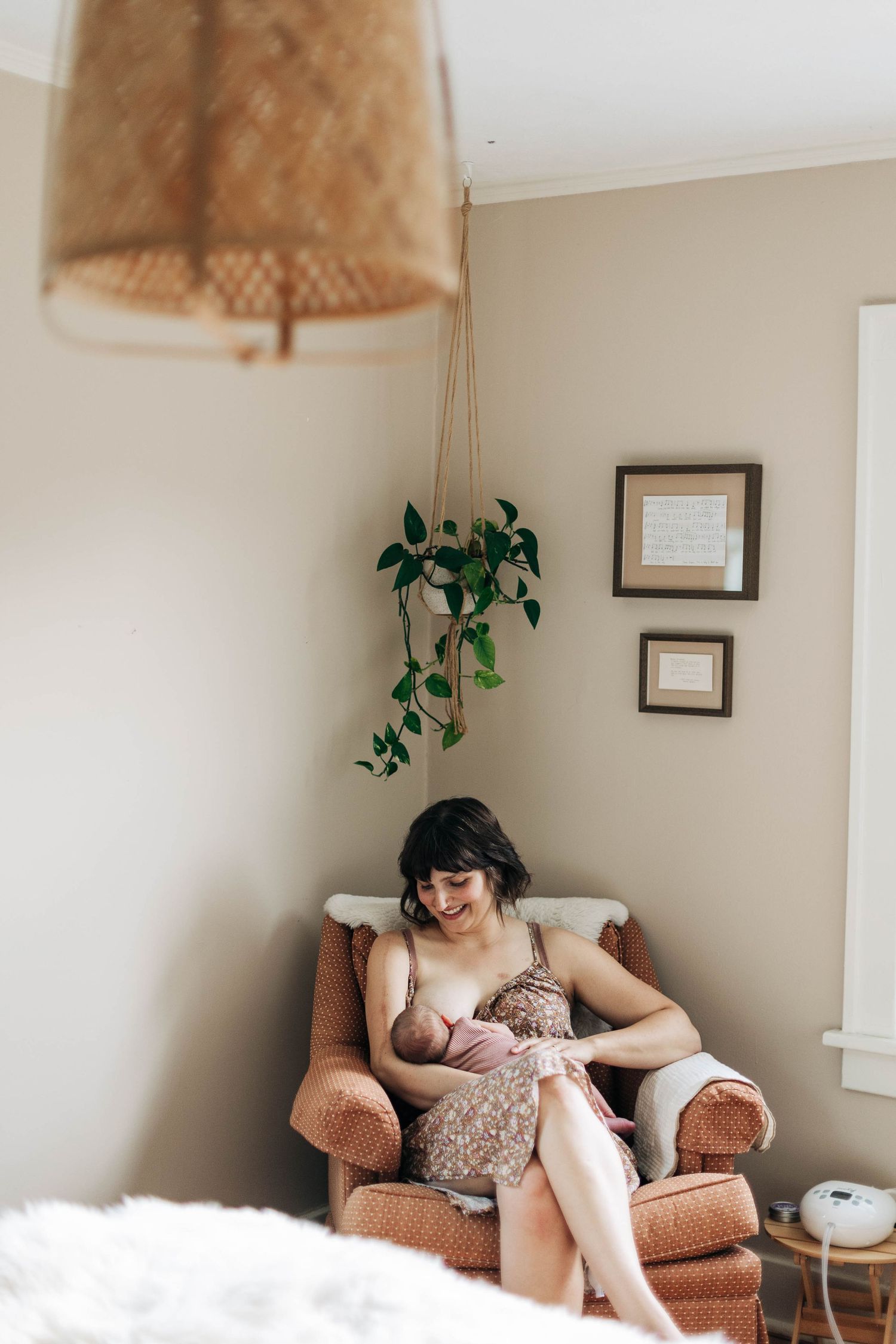 Tender nursing moment in cozy corner with hanging lamp and potted plants.