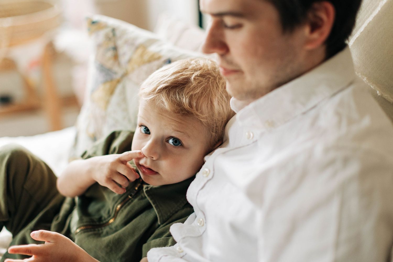 Intimate moment between parent and toddler relaxing together on couch.