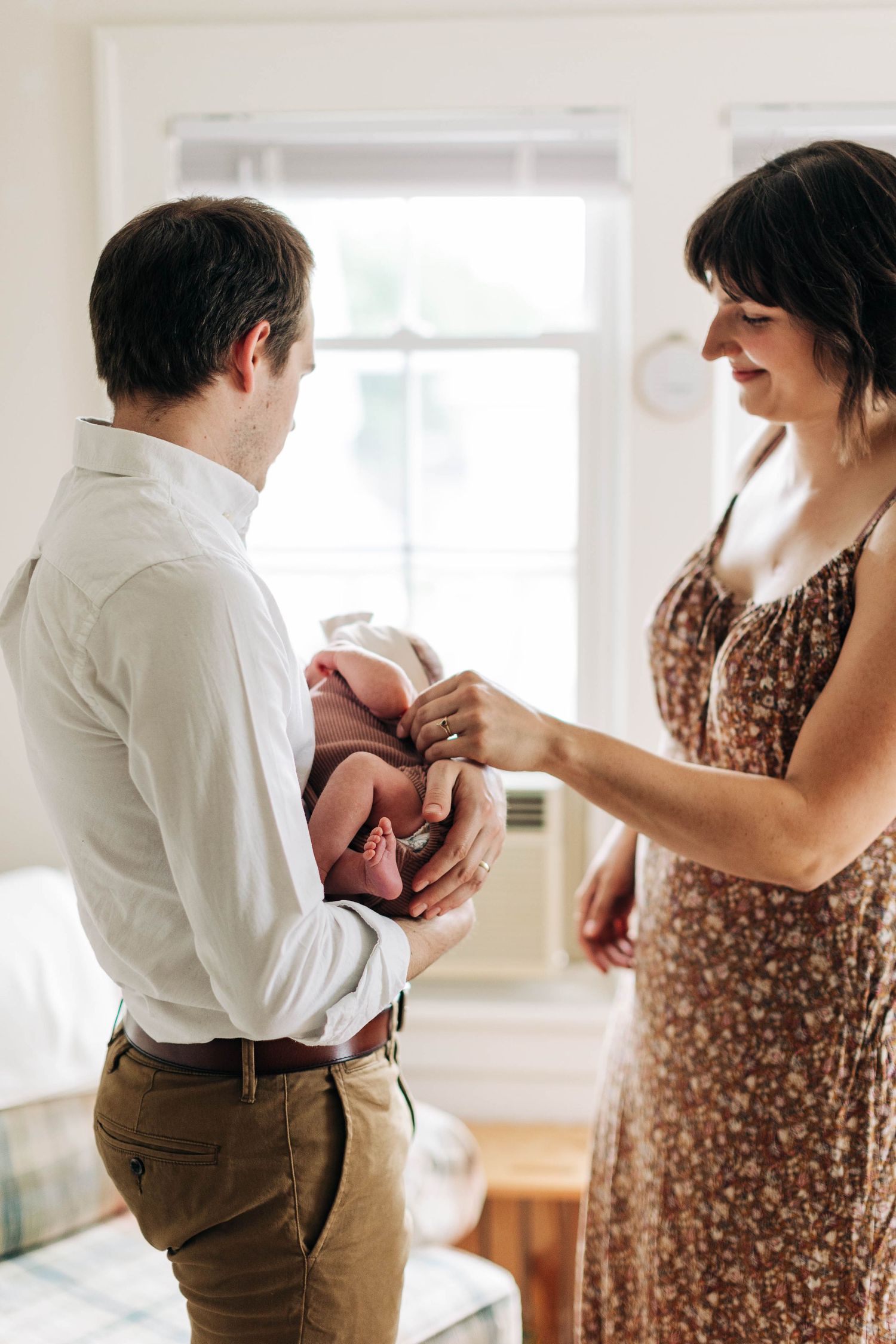 Intimate indoor moment with newborn between two people in natural window light.