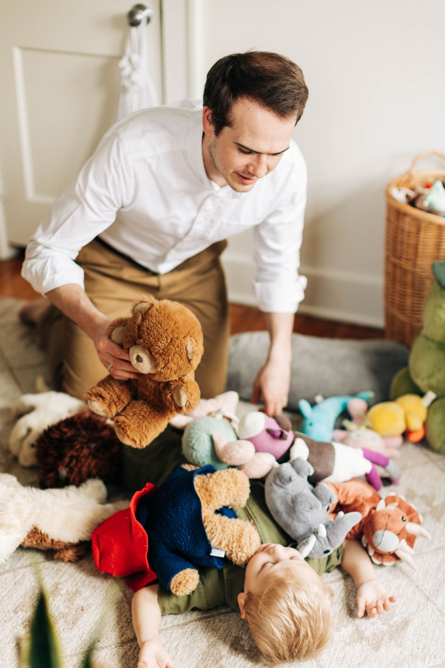 Playing with a collection of stuffed animals spread across the floor.