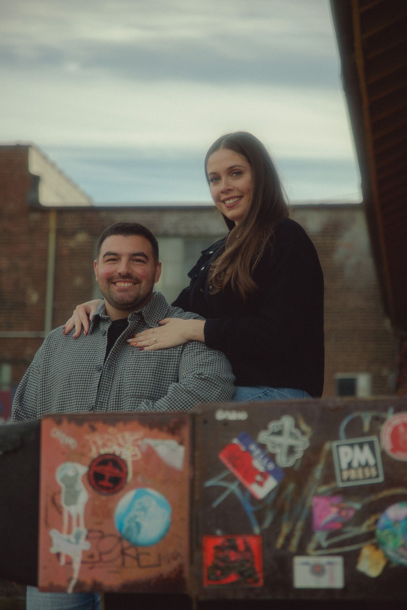 Couple poses playfully in front of colorful wall art murals during outdoor photoshoot.