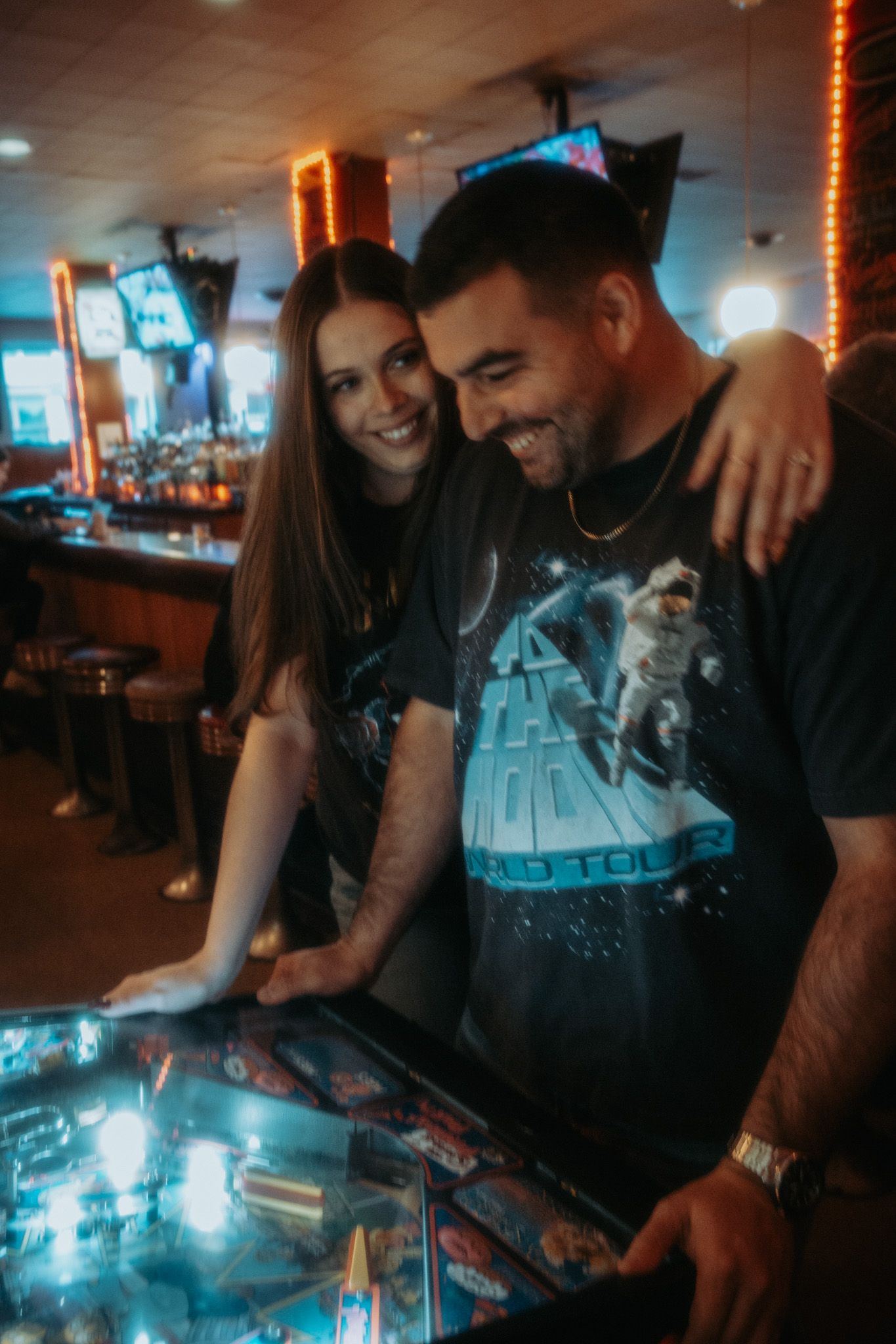 Couple enjoying time together playing arcade games in dimly lit entertainment venue.
