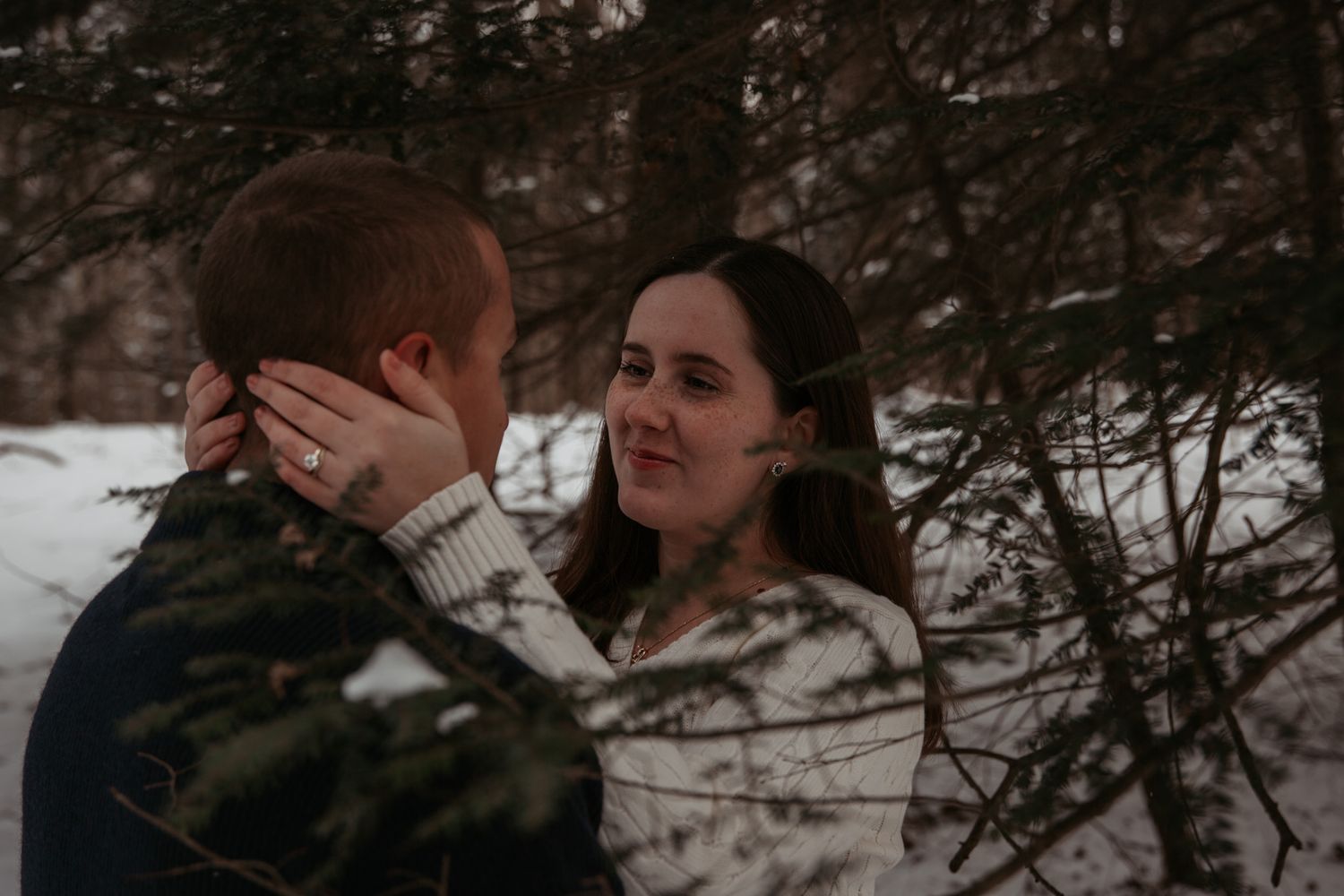An intimate moment between a couple in a snowy forest setting.