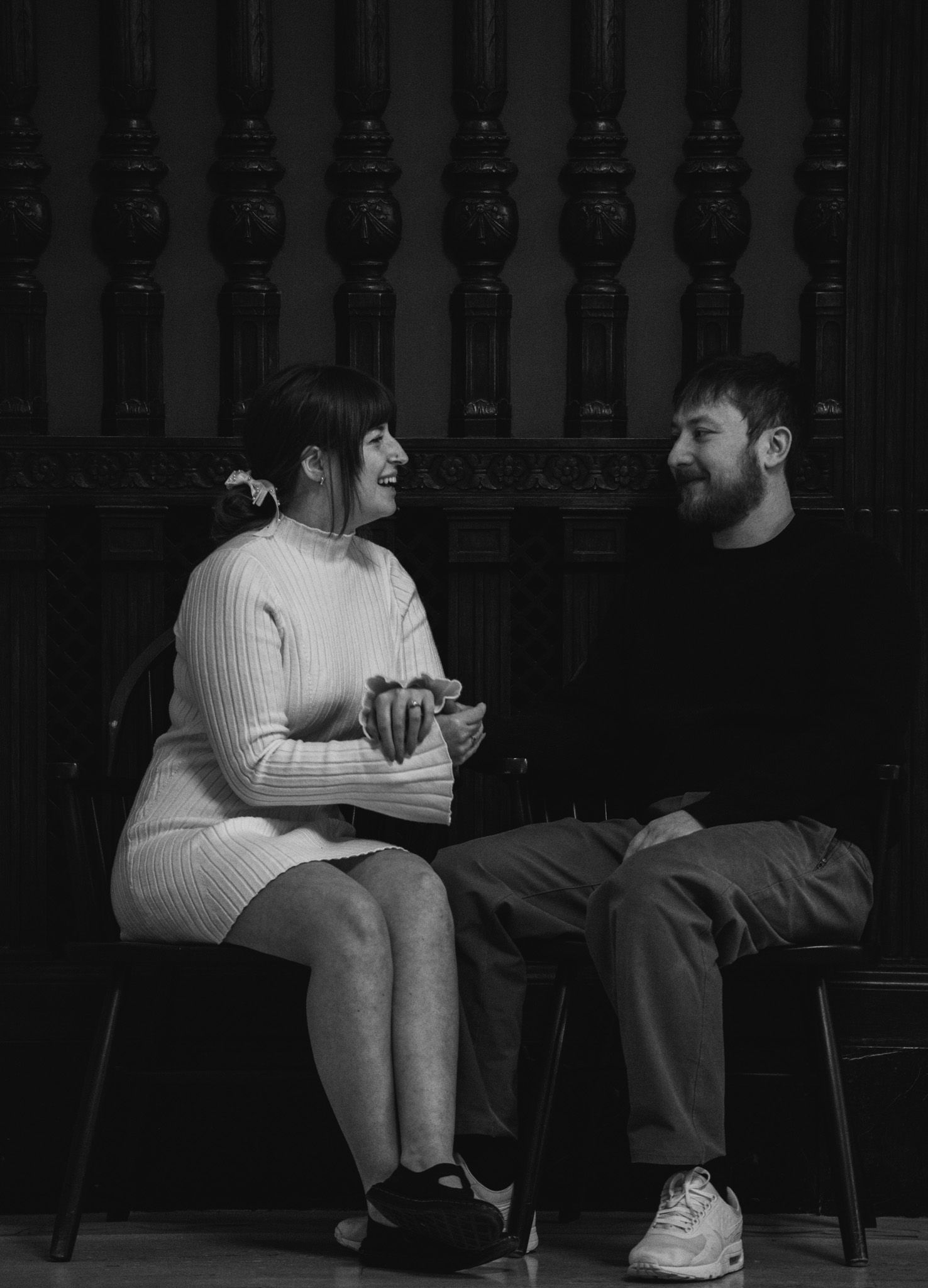 Black and white portrait of couple sitting and conversing in vintage architectural setting.