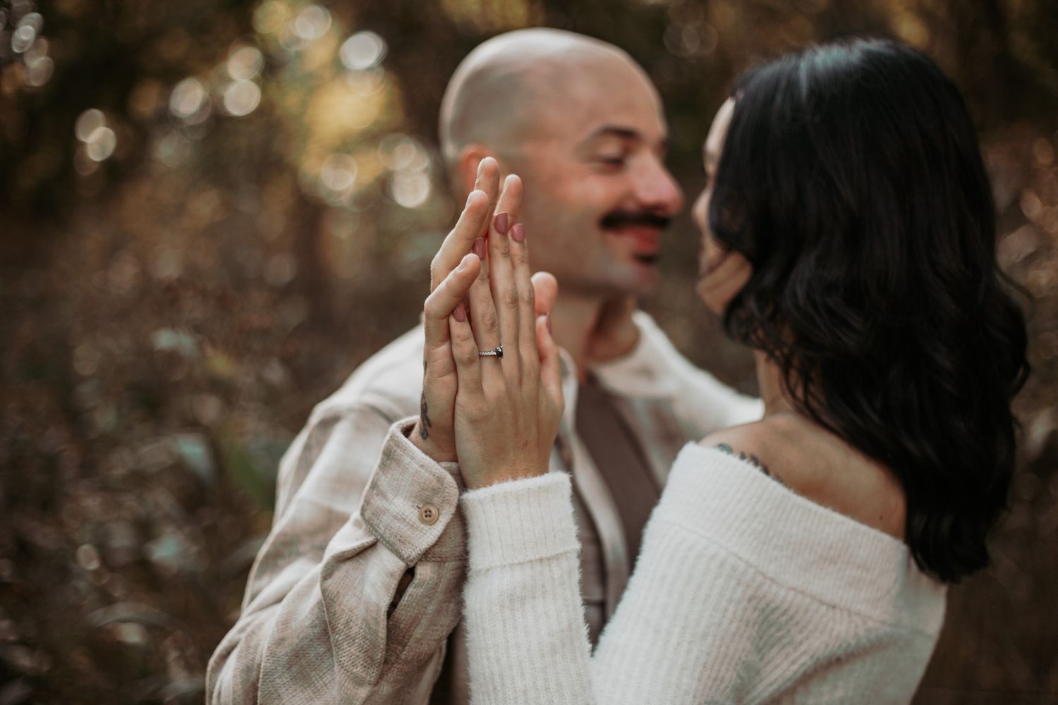 A couple shares intimate moments in white sweaters against a blurred background.