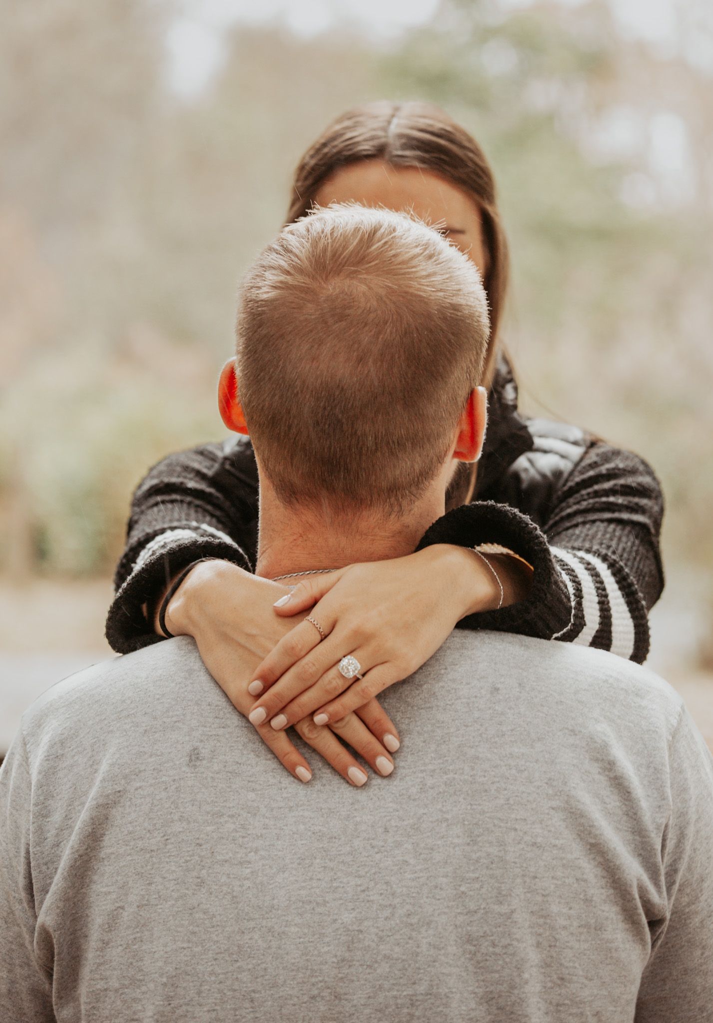 Close-up shots of hands embracing on a gray shirt against an outdoor backdrop.