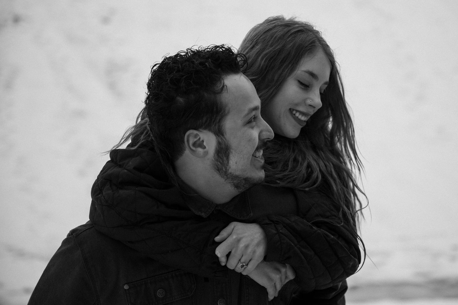Black and white portrait of couple sharing intimate embrace outdoors.