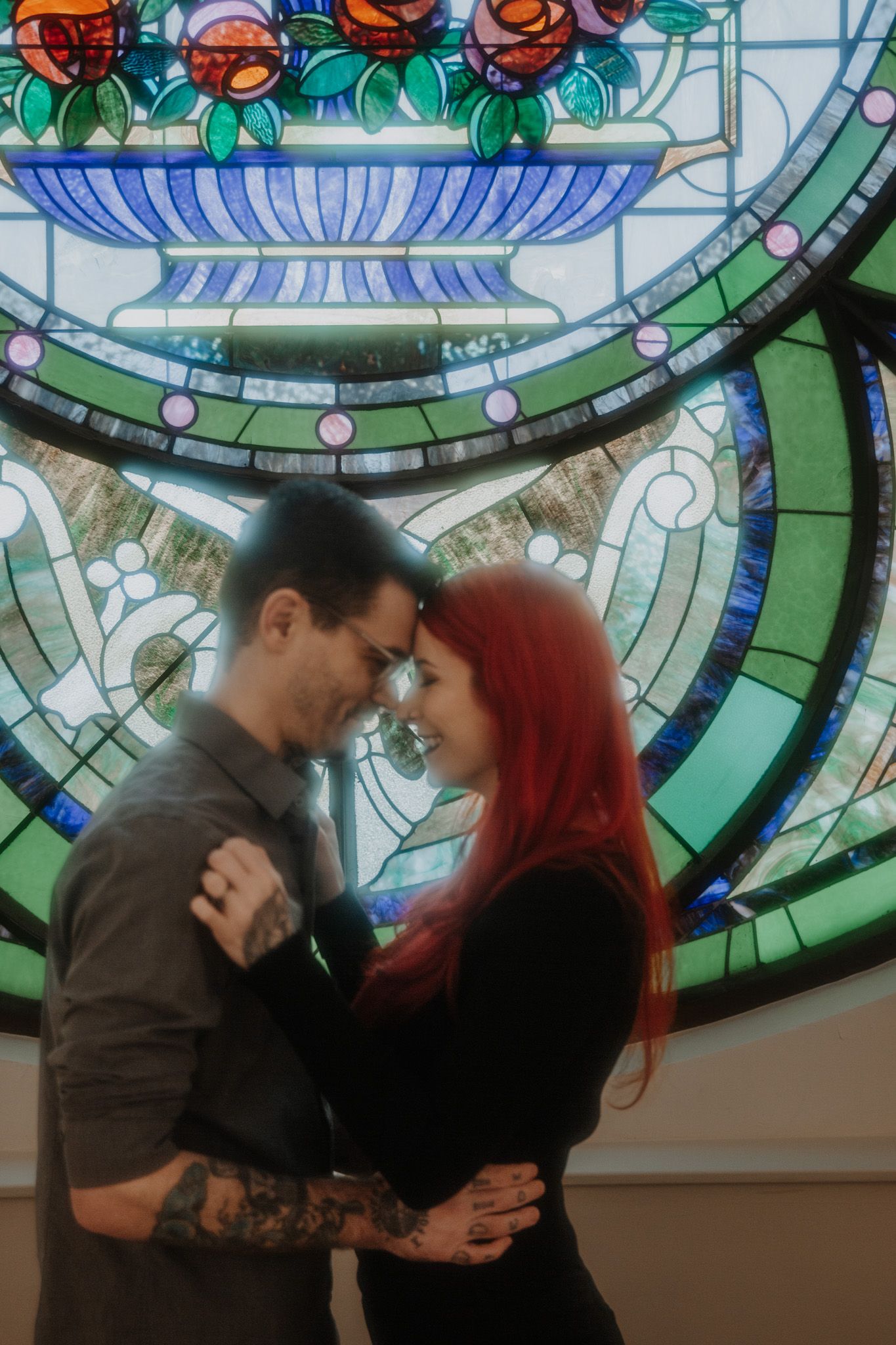 A romantic couple dancing together beneath beautiful stained glass artwork.