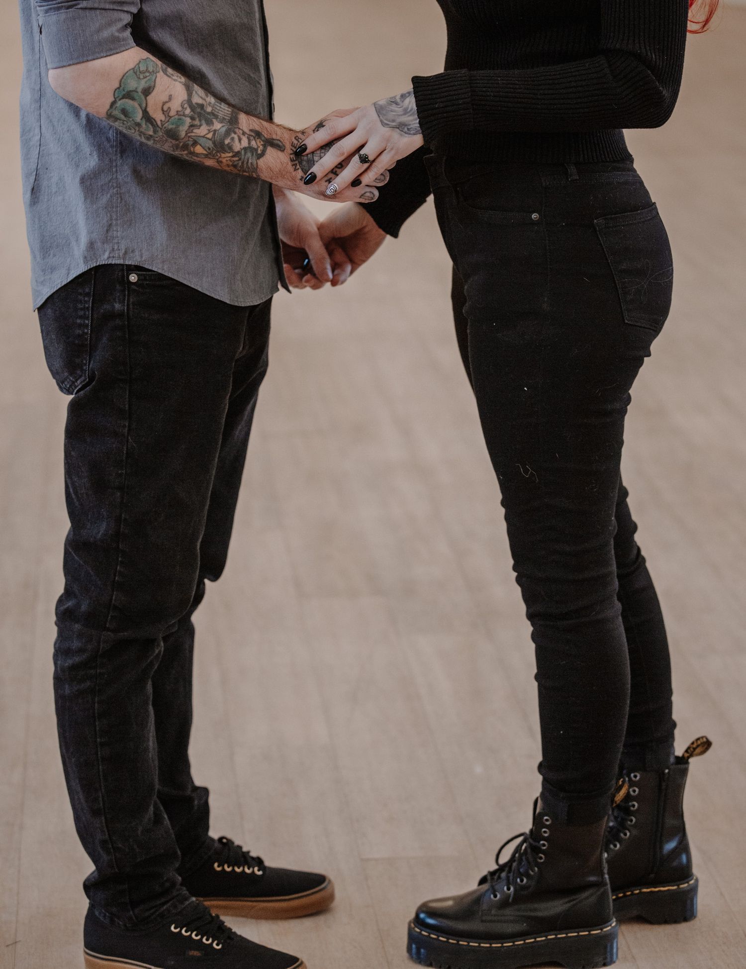 Close-up view of two people's feet standing close together on a plain floor.